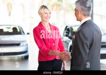 beautiful middle aged woman handshaking with car dealer Stock Photo