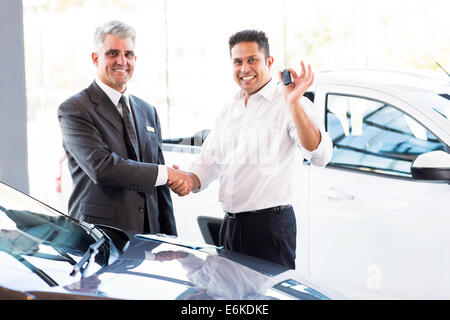 happy Indian man showing new car key while handshaking with salesman Stock Photo