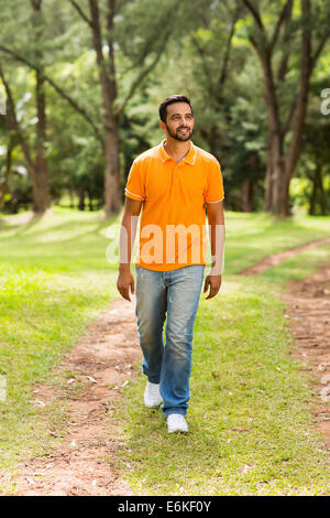 casual young Indian man walking in the park and looking away Stock Photo