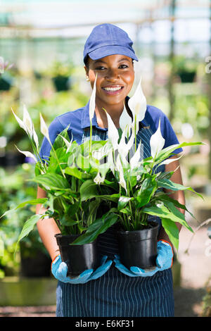 portrait of female African florist holding to potted plants Stock Photo