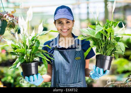 pretty female gardener holding two potted flowers in a garden center Stock Photo