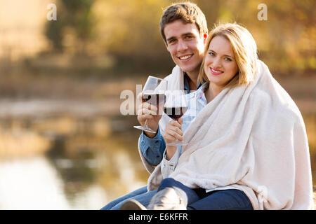 beautiful young couple snuggle outdoors with glass of wine