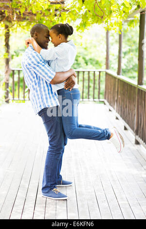 playful young African couple hugging under grape vines Stock Photo
