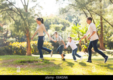 playful family hand in hand running in forest Stock Photo