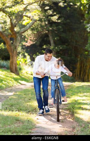 loving father teaching daughter to ride bike Stock Photo