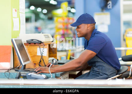 happy African male cashier working at till point in supermarket Stock Photo