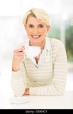 pretty middle aged woman drinking coffee at home Stock Photo