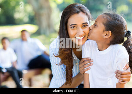 cute little Indian girl kissing her mother outdoors Stock Photo