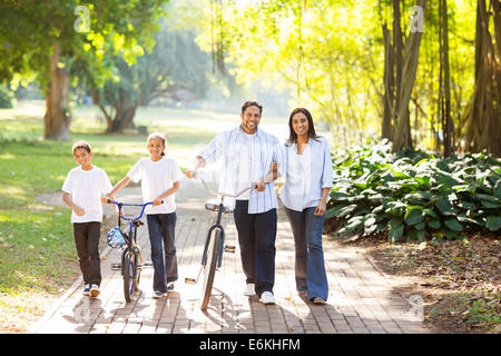 happy Indian family of four walking outdoors in the park Stock Photo