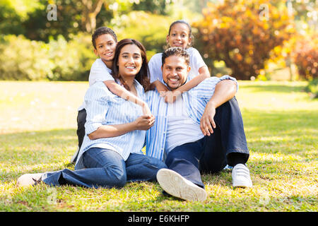 happy Indian family sitting on grass in the park Stock Photo