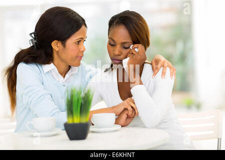 loving middle aged African woman comforting her sad daughter at home Stock Photo