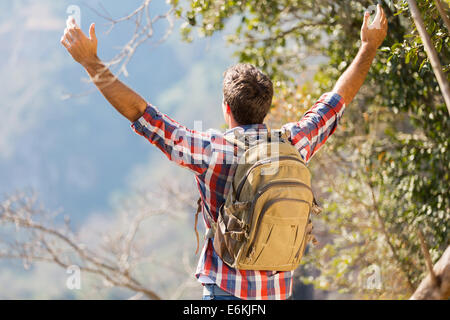 rear view of young hiker with arms open on top of the mountain Stock Photo