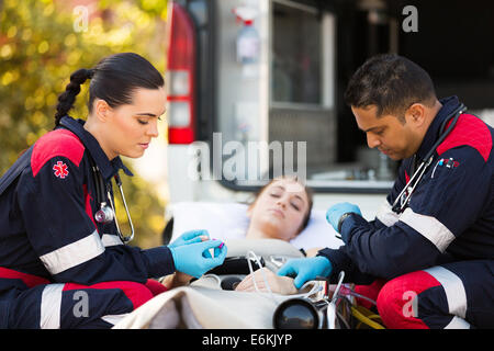 professional paramedics giving unconscious young woman first aid Stock Photo