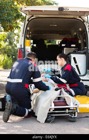 Paramedic putting oxygen mask on unconscious patient Stock Photo