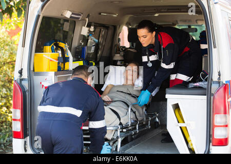 emergency medical staff team transporting patient to hospital with ambulance Stock Photo