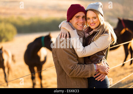 portrait of happy farm couple hugging in horse ranch Stock Photo