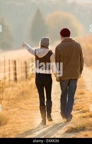 rear view of young couple walking in country road Stock Photo