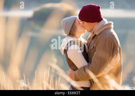 loving young couple kissing by the lake in winter morning