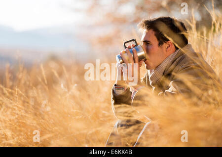 peaceful young man drinking coffee in autumn by the lake Stock Photo