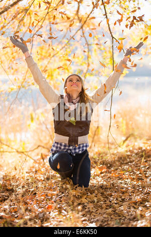 happy young woman throws autumn leaves in forest Stock Photo