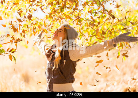 autumn leaves falling on happy young woman in forest Stock Photo