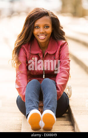 stylish African woman sitting outdoors in the city Stock Photo