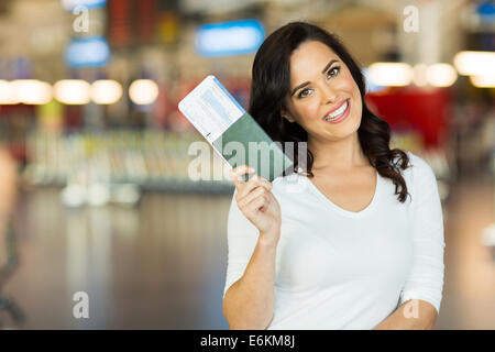 portrait of happy young woman holding passport and boarding pass at airport Stock Photo