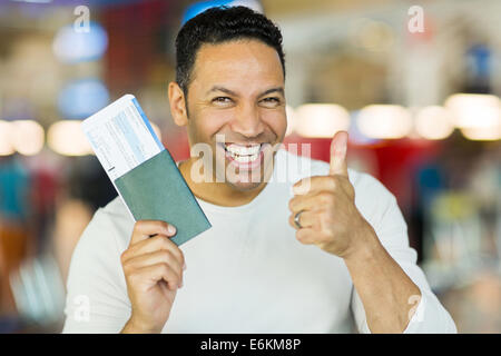 mid age man holding boarding pass and giving thumb up Stock Photo
