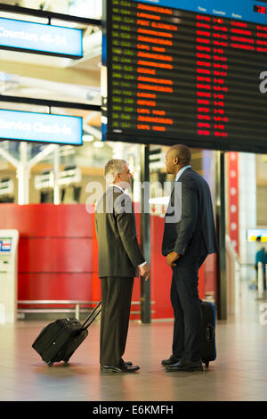 two businessmen in front of airport information board Stock Photo