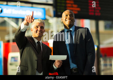 handsome business travellers pointing at flight information board Stock Photo