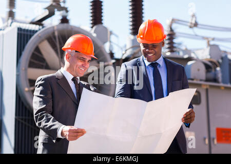 power plant managers holding blueprint at substation Stock Photo