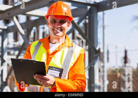 handsome middle aged electrician holding clipboard in electricity power plant Stock Photo