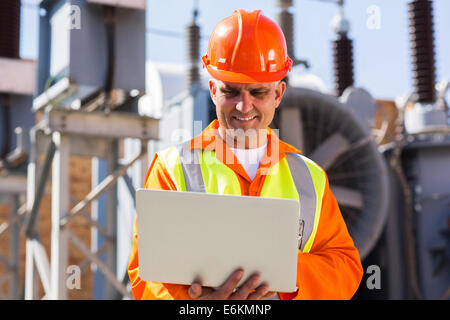 mid age engineer using laptop computer in electricity power plant Stock Photo