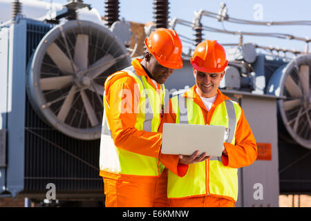 electrical engineers using laptop computer in electric substation Stock Photo