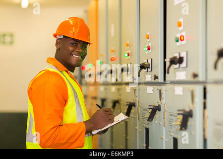 happy young African industrial technician taking machine readings Stock Photo