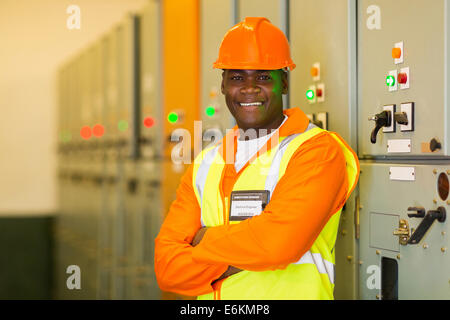 professional African industrial technician in front of control panel Stock Photo