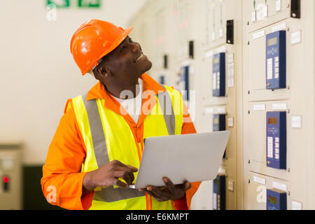 smiling African male industrial engineer using laptop in control room Stock Photo