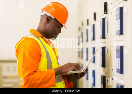 handsome young African control room engineer using laptop Stock Photo