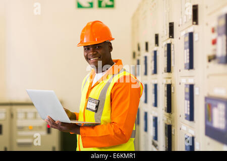 African electrical engineer using laptop computer in power plant control room Stock Photo