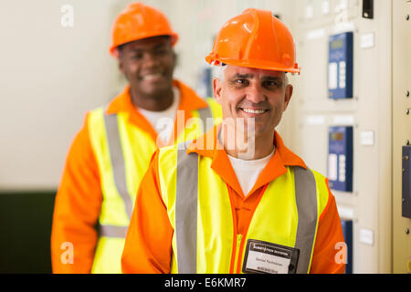 handsome senior industrial technician with colleague on background in control room Stock Photo