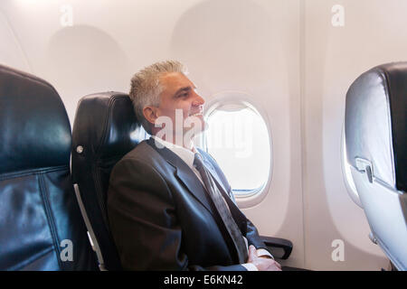 happy middle aged airplane passenger relaxing during flight on air plane Stock Photo