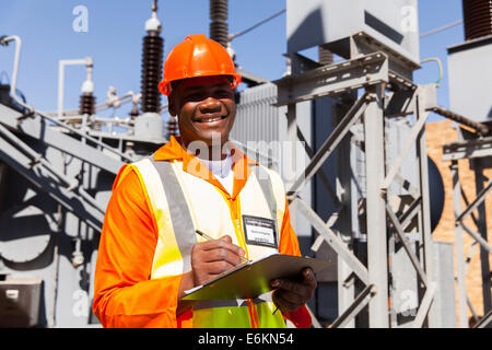 handsome young African electrical engineer holding clipboard in power station Stock Photo