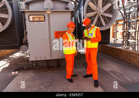 two electrical engineers working together in front of transformer Stock Photo