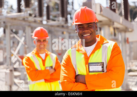 handsome young African American electrical engineer with arms crossed in substation Stock Photo