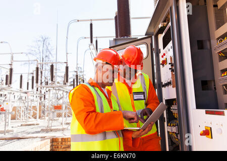 two electrical engineers using laptop computer next to transformer Stock Photo