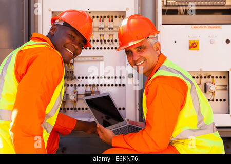 modern electrical co-workers using laptop computer checking transformer Stock Photo