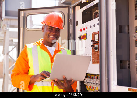 portrait of happy young African electrical engineer with laptop Stock Photo