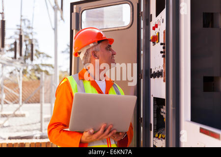 experienced senior electrician working on a transformer in substation Stock Photo
