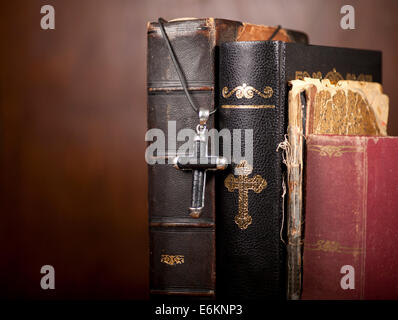 Old Holy Bibles and cross on wooden background. Stock Photo