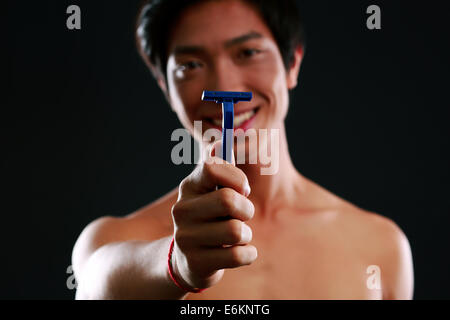 Asian man holding razor. Focus on razor Stock Photo